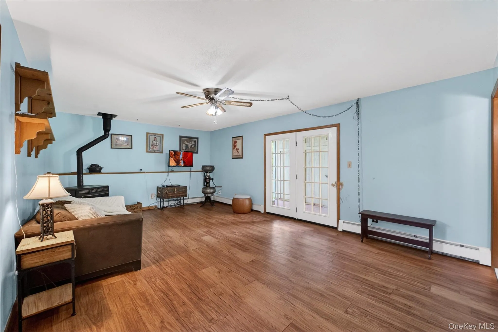 Spacious interior featuring wood-finish flooring, light blue walls, Pellet Stove and white trim Spacious interior featuring wood-finish flooring, light blue walls, Pellet Stove and white trim