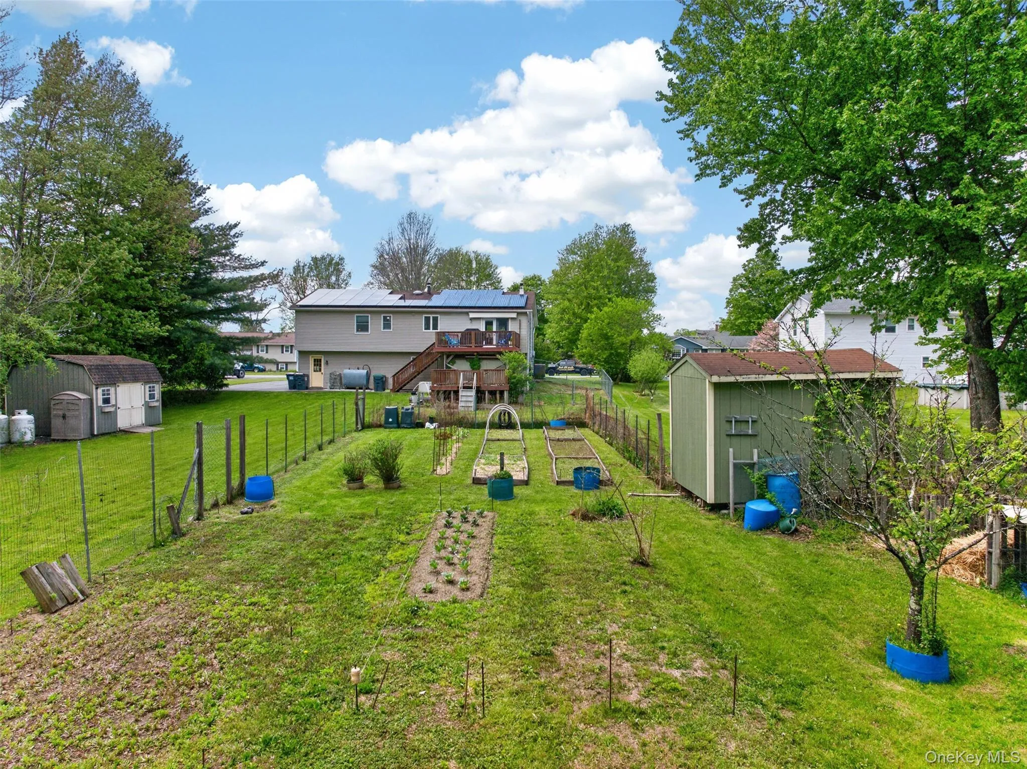 Expansive backyard with multiple garden beds, a fenced perimeter, and mature trees Expansive backyard with multiple garden beds, a fenced perimeter, and mature trees