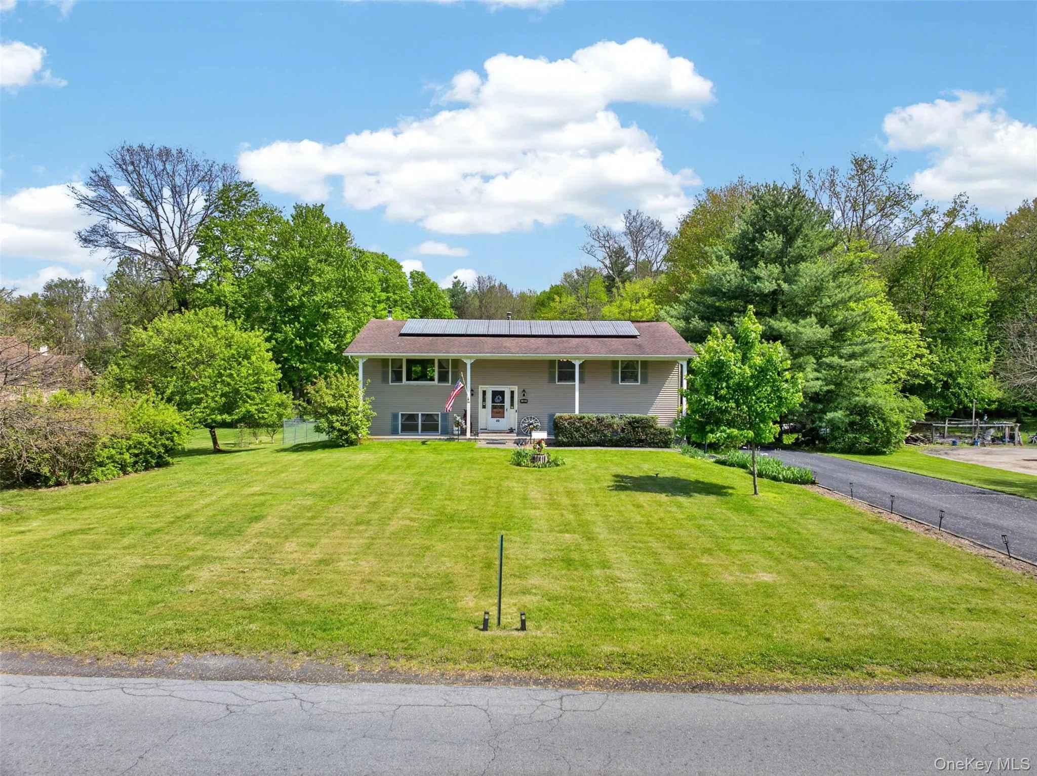Split-level residence featuring a covered front entry, solar panels, and a paved driveway Split-level residence featuring a covered front entry, solar panels, and a paved driveway