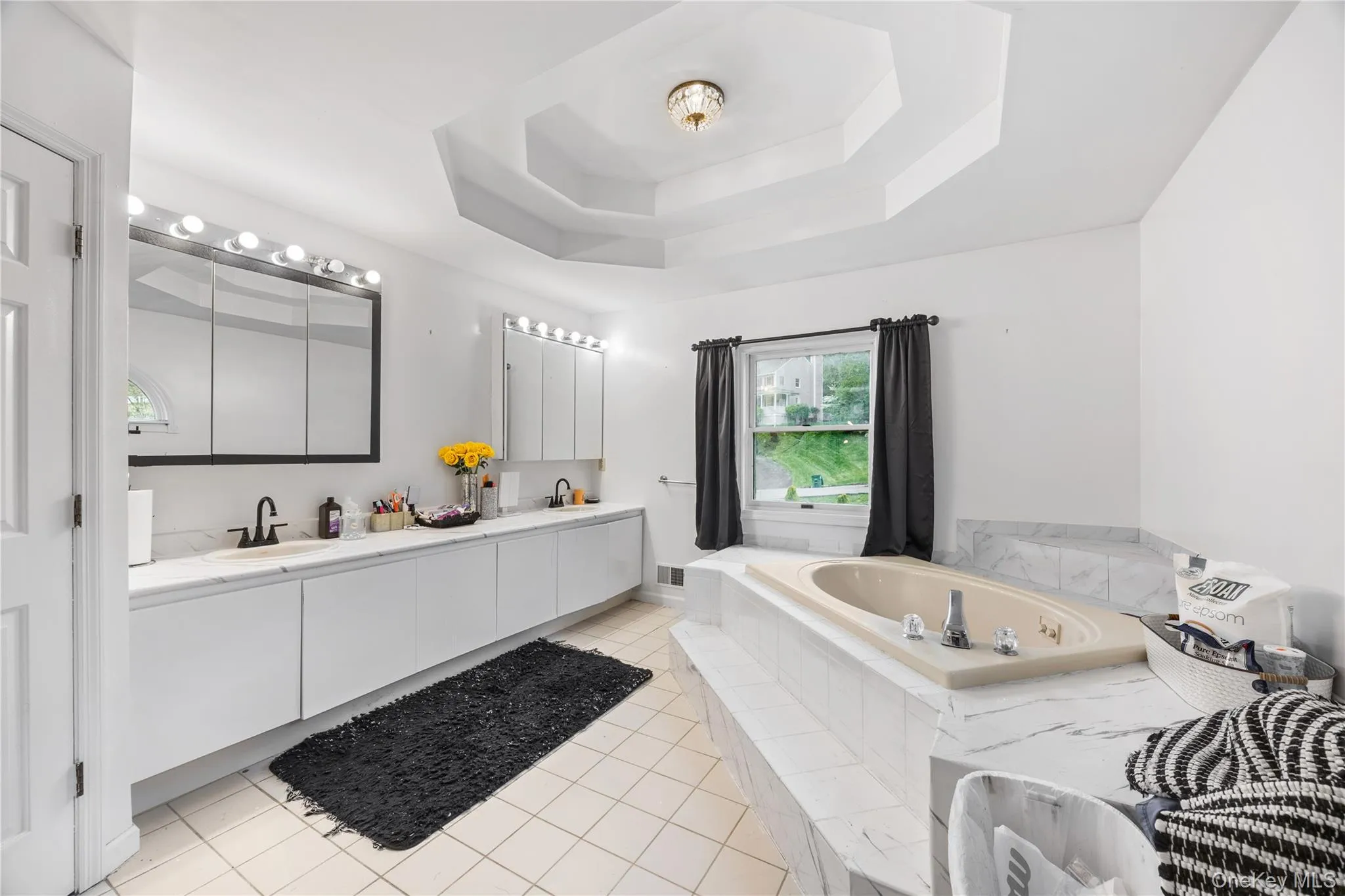 Recessed tub with tiled surround, dual vanity with undermount sinks, and a tray ceiling Recessed tub with tiled surround, dual vanity with undermount sinks, and a tray ceiling