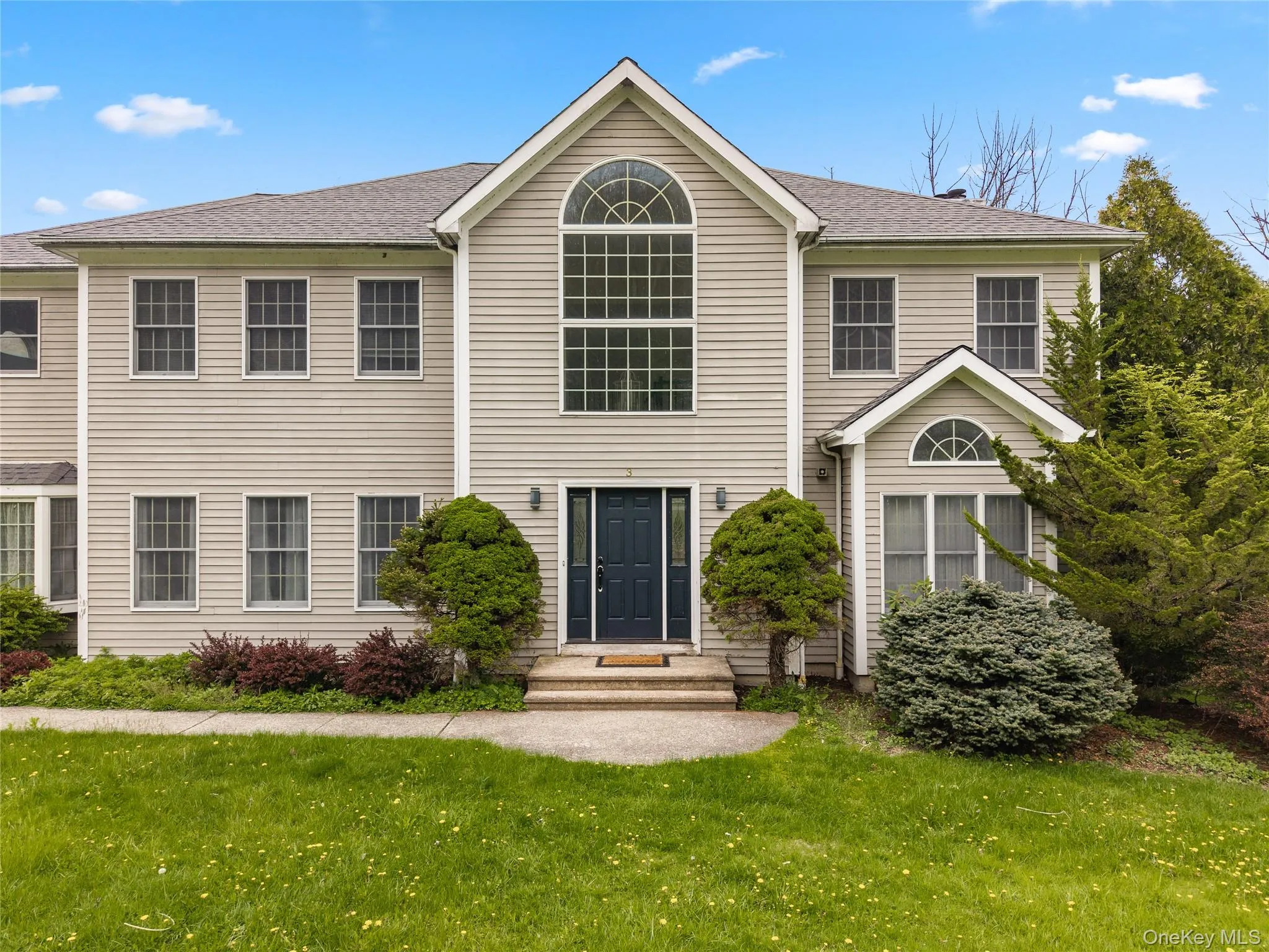 Two-story residence featuring light-toned siding, a prominent arched window, and multiple pane windows Two-story residence featuring light-toned siding, a prominent arched window, and multiple pane windows
