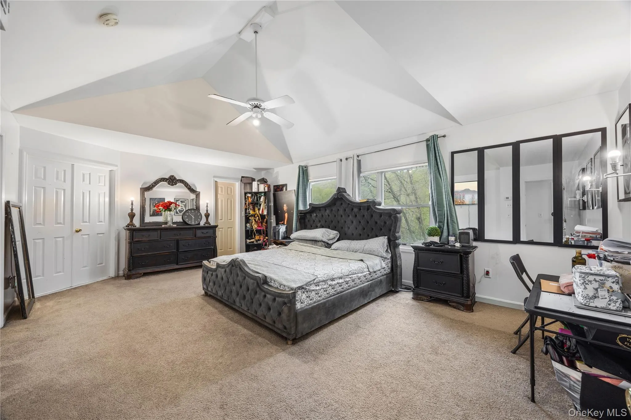 Vaulted ceiling featuring a ceiling fan, broad windows, and plush carpet flooring Vaulted ceiling featuring a ceiling fan, broad windows, and plush carpet flooring