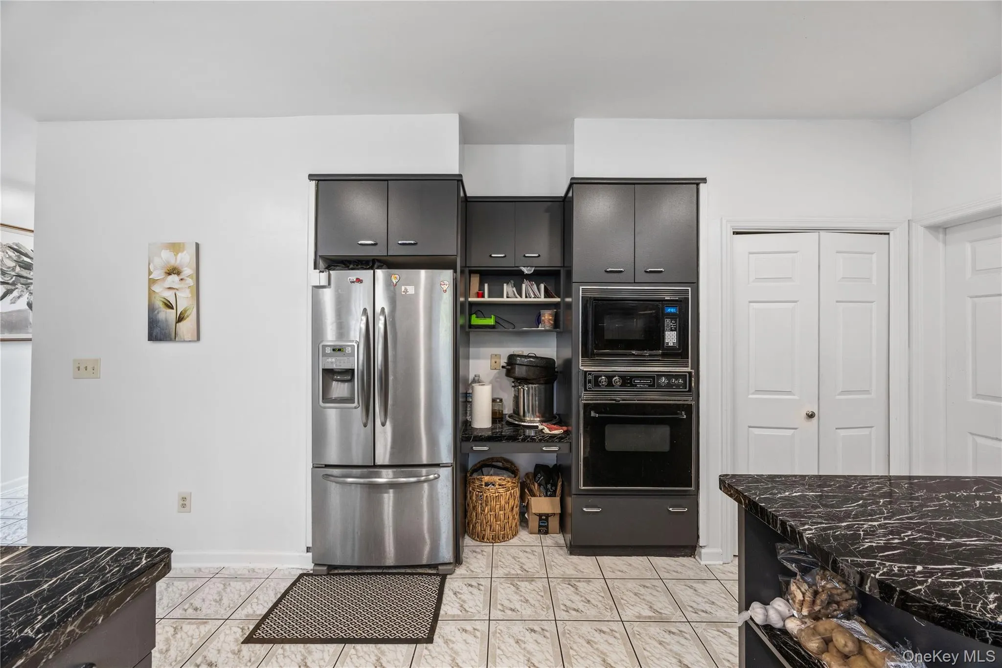 Stainless steel French door refrigerator, black wall oven, and built-in microwave complement the dark cabinetry Stainless steel French door refrigerator, black wall oven, and built-in microwave complement the dark cabinetry