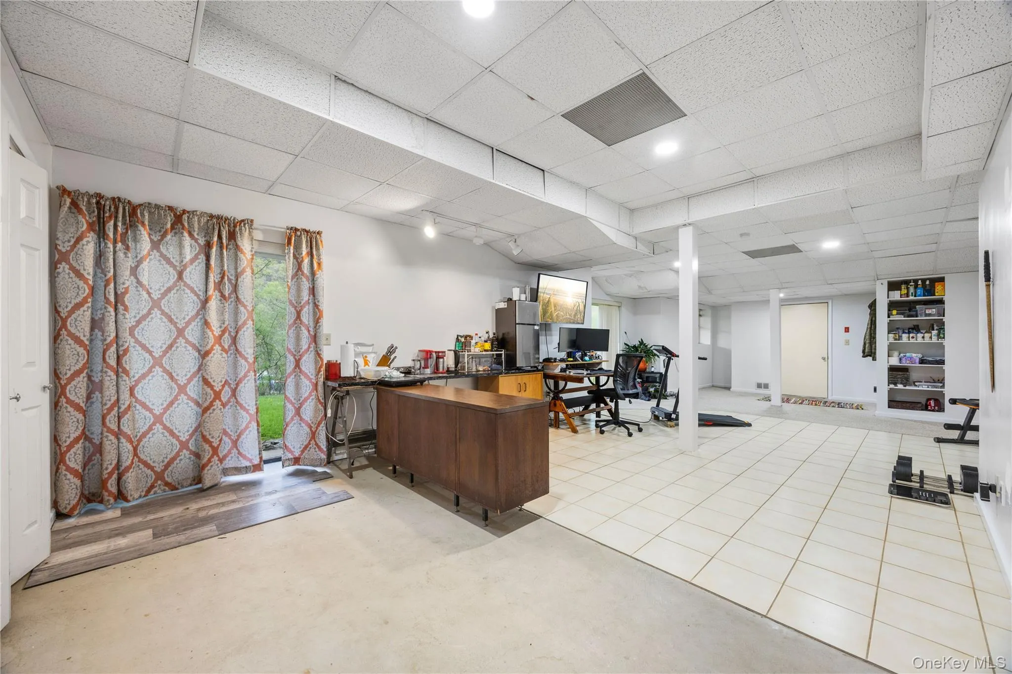 Spacious finished basement featuring a drop ceiling with recessed lighting, tile flooring, and a sliding glass door to the exterior Spacious finished basement featuring a drop ceiling with recessed lighting, tile flooring, and a sliding glass door to the exterior