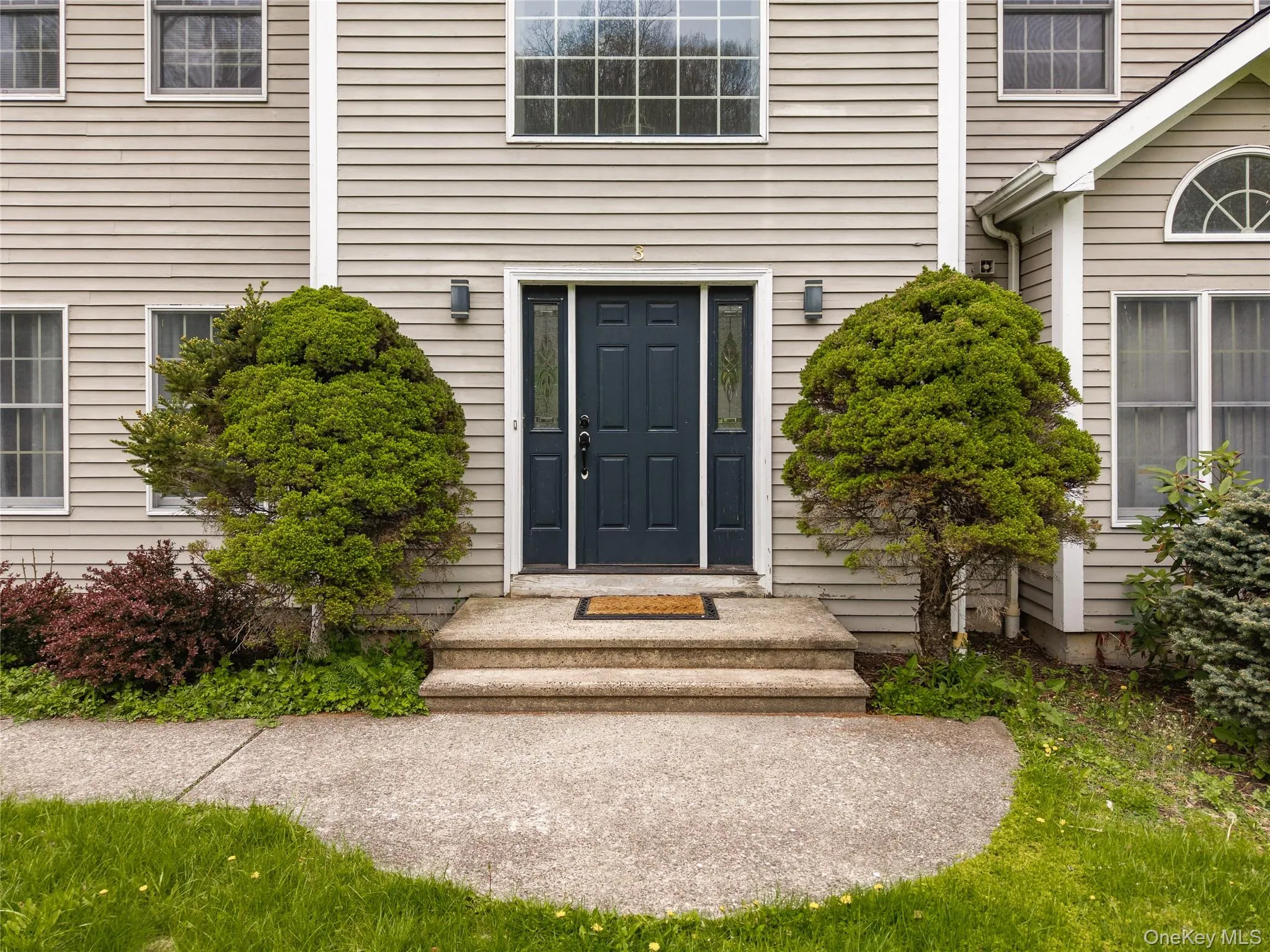 Stone steps ascend to a dark blue entry door with sidelight windows Stone steps ascend to a dark blue entry door with sidelight windows