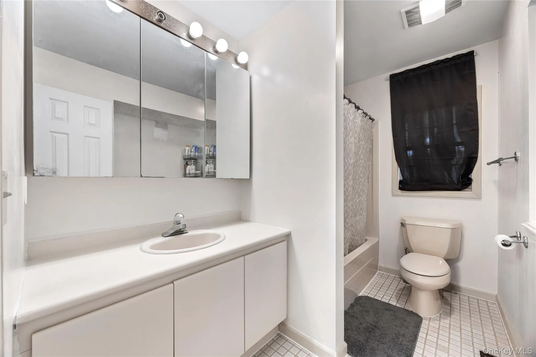 Bathroom featuring a vanity with integrated sink, wall-mounted mirror cabinet, and overhead vanity lighting Bathroom featuring a vanity with integrated sink, wall-mounted mirror cabinet, and overhead vanity lighting