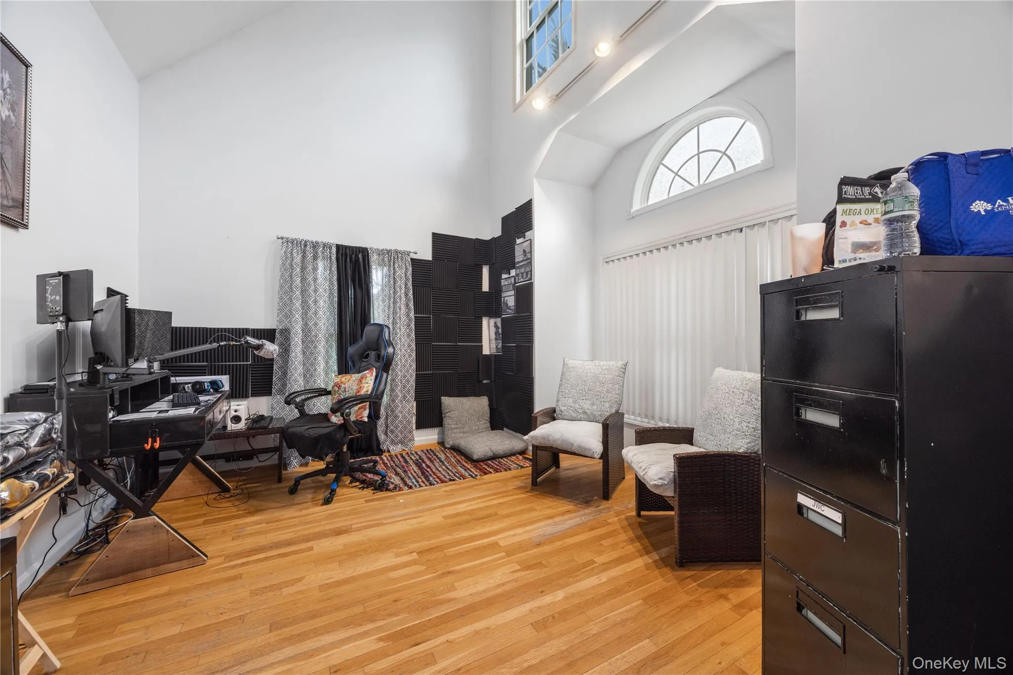 Vaulted ceilings featuring recessed lighting, a prominent arched window, and wood-finish flooring Vaulted ceilings featuring recessed lighting, a prominent arched window, and wood-finish flooring