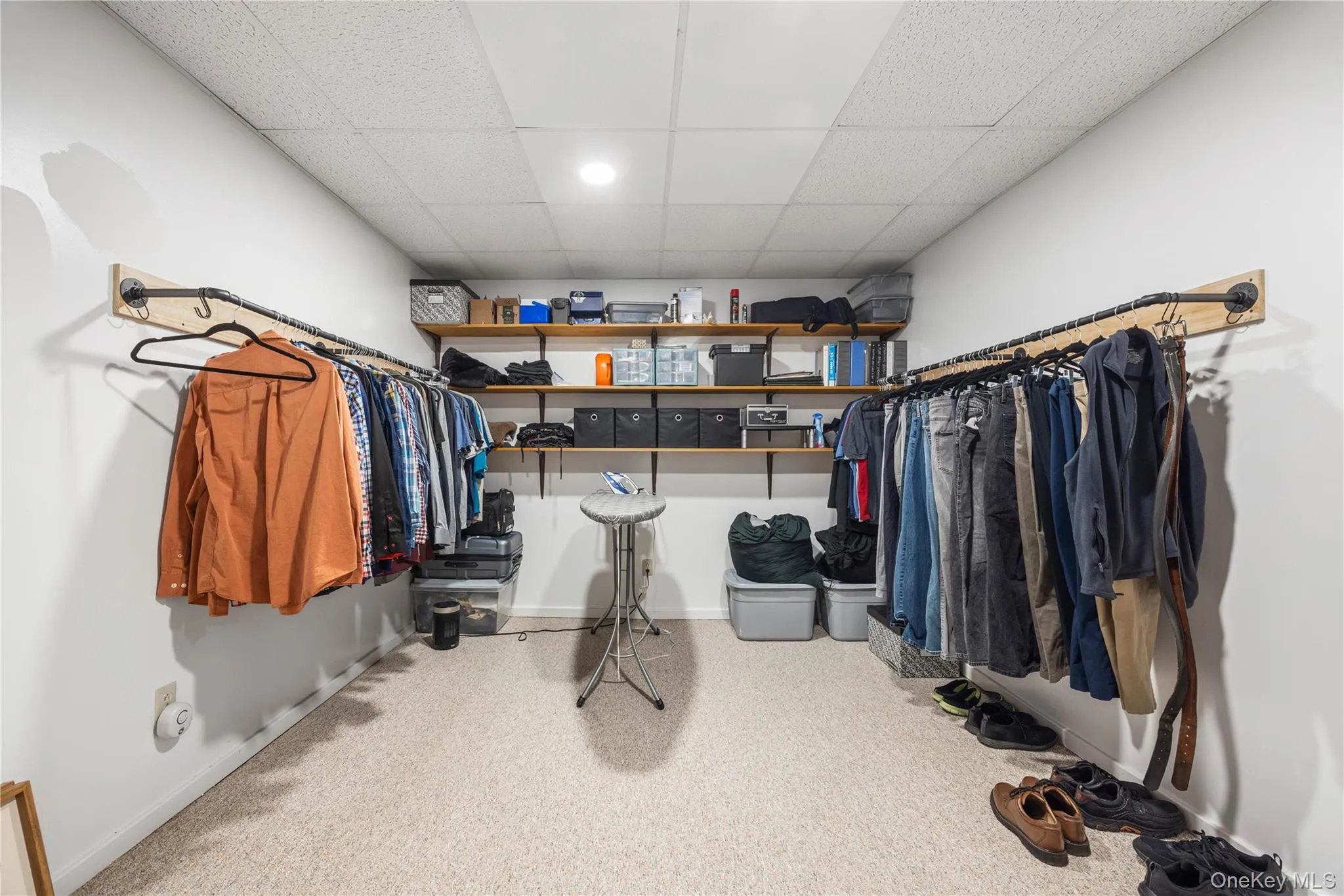 Customizable open closet system with integrated shelving, recessed lighting, and neutral carpeting Customizable open closet system with integrated shelving, recessed lighting, and neutral carpeting