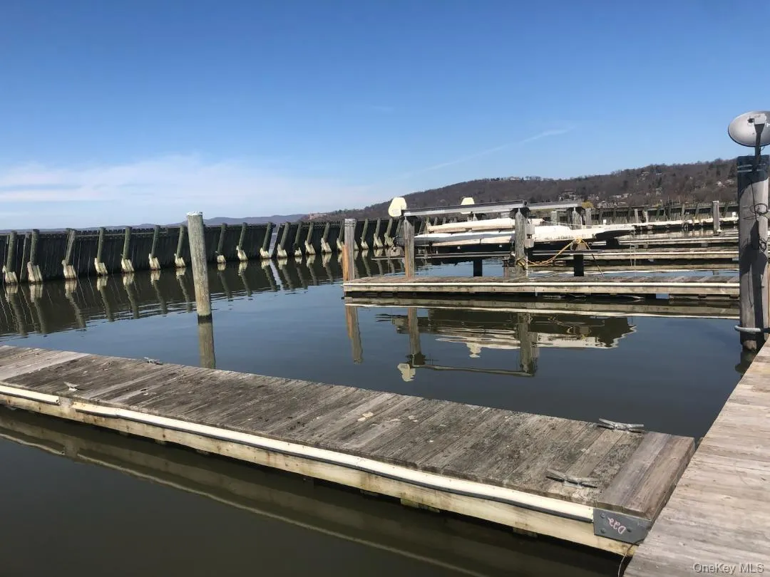 Waterfront property featuring extensive dockage, a protective wave barrier, multiple boat slips, and a hillside backdrop Waterfront property featuring extensive dockage, a protective wave barrier, multiple boat slips, and a hillside backdrop