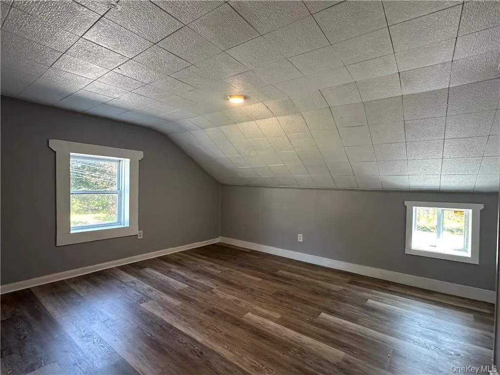 Bonus room with a wealth of natural light, lofted ceiling, and dark hardwood / wood-style flooring Bonus room with a wealth of natural light, lofted ceiling, and dark hardwood / wood-style flooring