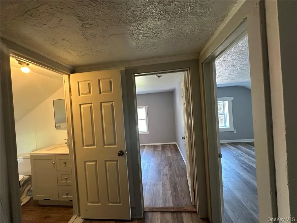 Corridor featuring a textured ceiling, plenty of natural light, and dark hardwood / wood-style flooring Corridor featuring a textured ceiling, plenty of natural light, and dark hardwood / wood-style flooring