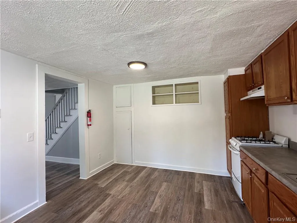 Kitchen featuring dark wood-type flooring, a textured ceiling, and white range with gas cooktop Kitchen featuring dark wood-type flooring, a textured ceiling, and white range with gas cooktop