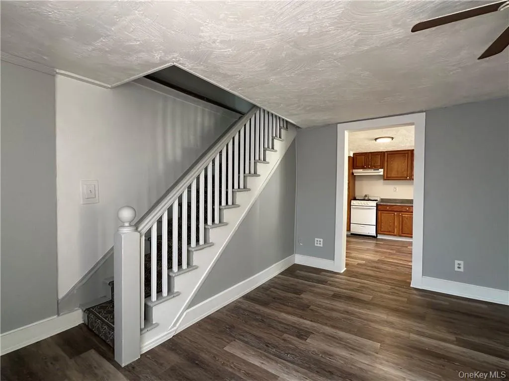 Stairway featuring wood-type flooring, a textured ceiling, and ceiling fan Stairway featuring wood-type flooring, a textured ceiling, and ceiling fan