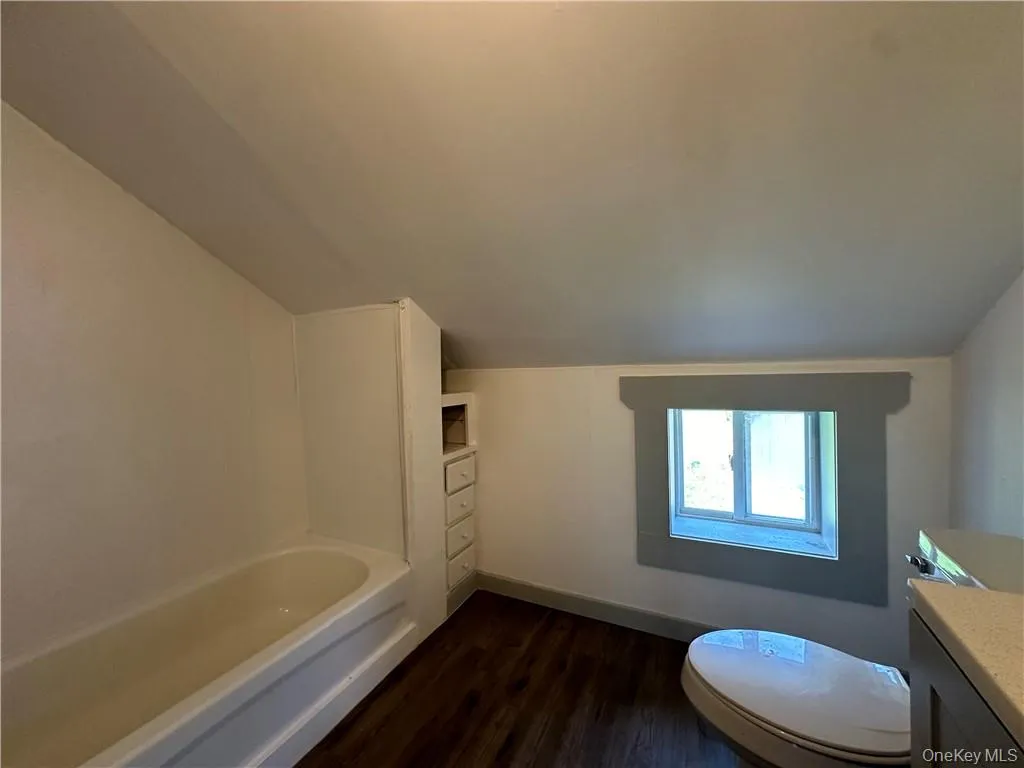 Full bathroom featuring vanity, lofted ceiling, toilet, bathtub / shower combination, and hardwood / wood-style floors Full bathroom featuring vanity, lofted ceiling, toilet, bathtub / shower combination, and hardwood / wood-style floors