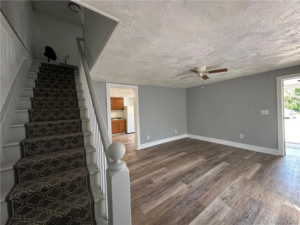 Staircase featuring a textured ceiling, hardwood / wood-style flooring, and ceiling fan Staircase featuring a textured ceiling, hardwood / wood-style flooring, and ceiling fan
