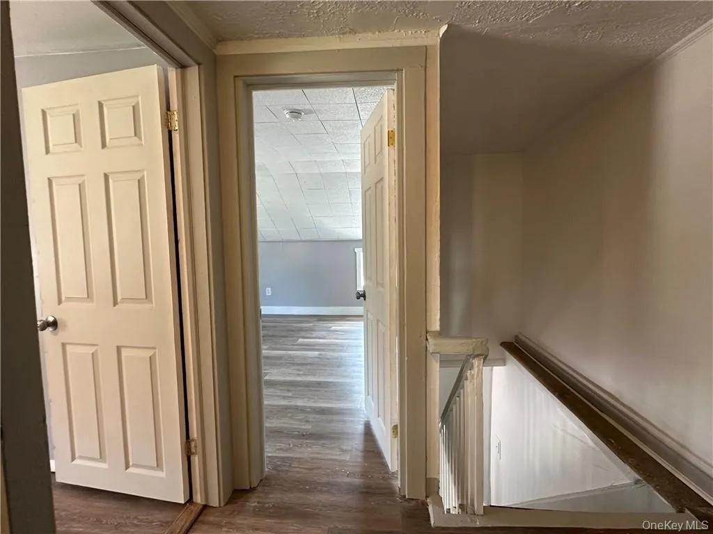 Hallway with a textured ceiling and dark hardwood / wood-style flooring Hallway with a textured ceiling and dark hardwood / wood-style flooring