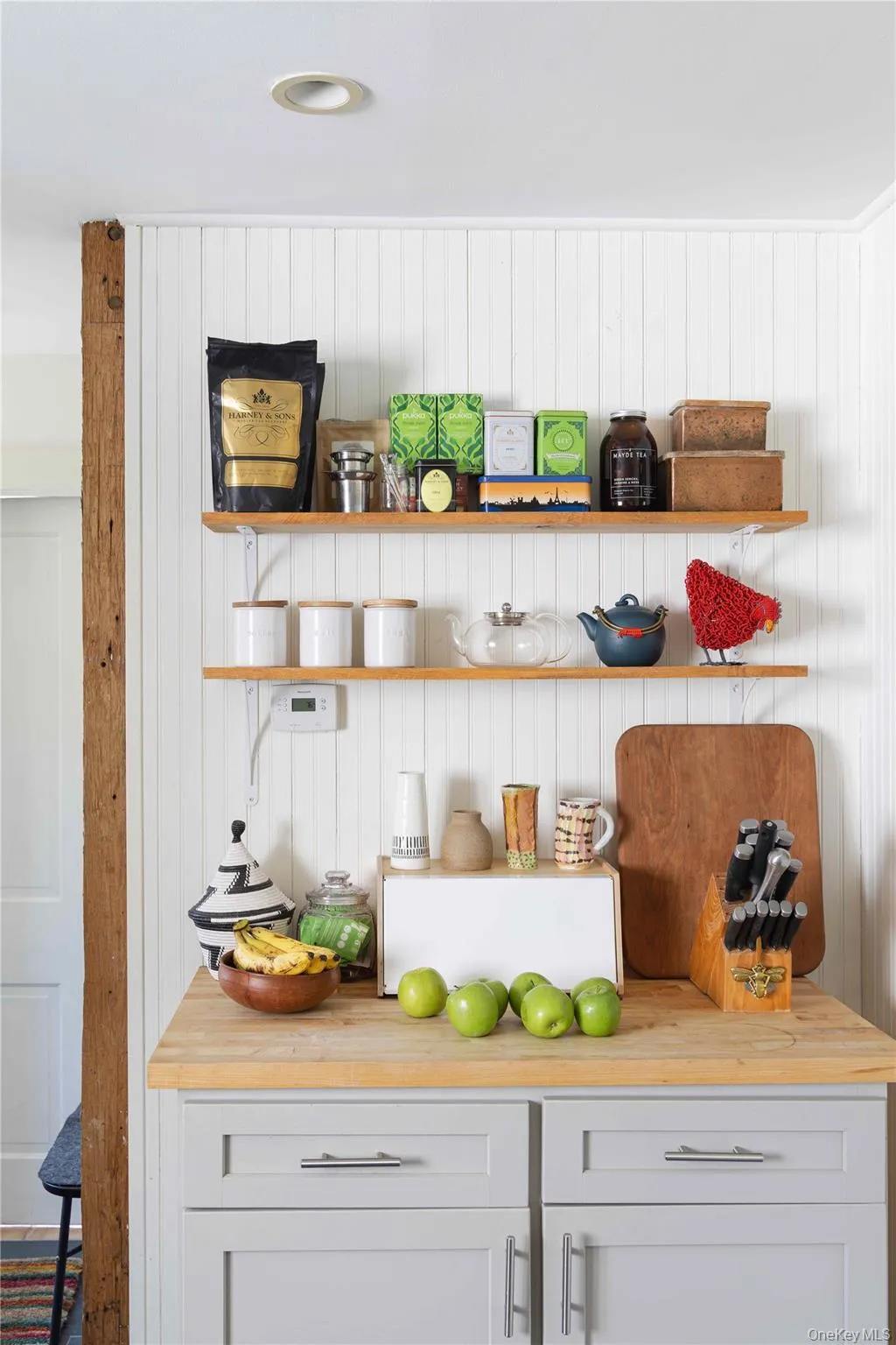 Kitchen area featuring light gray cabinetry with brushed nickel hardware, a wood-finish countertop, and open shelving Kitchen area featuring light gray cabinetry with brushed nickel hardware, a wood-finish countertop, and open shelving