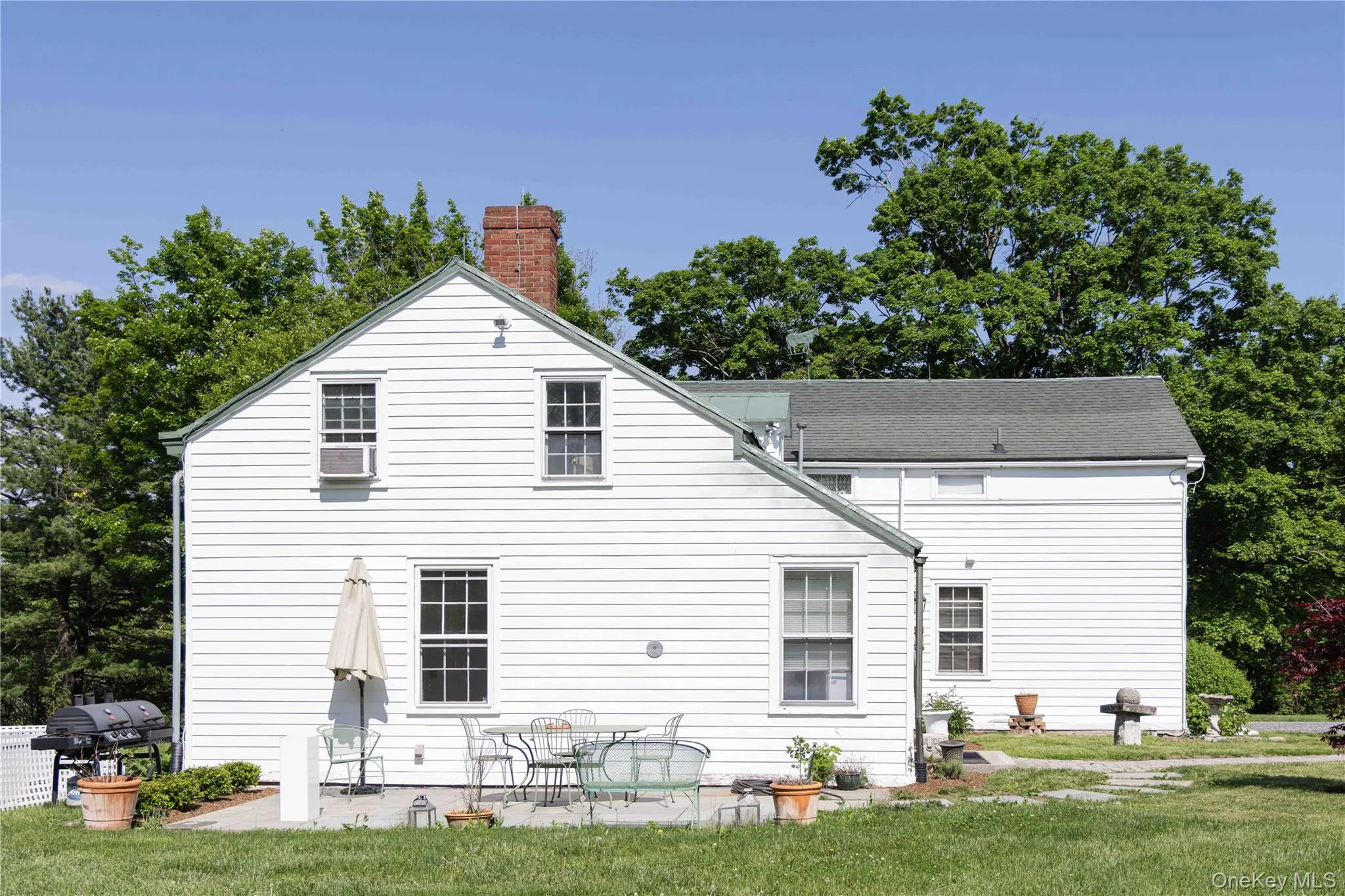 White clapboard siding exterior with a brick chimney, gabled roofline, and multiple window openings White clapboard siding exterior with a brick chimney, gabled roofline, and multiple window openings