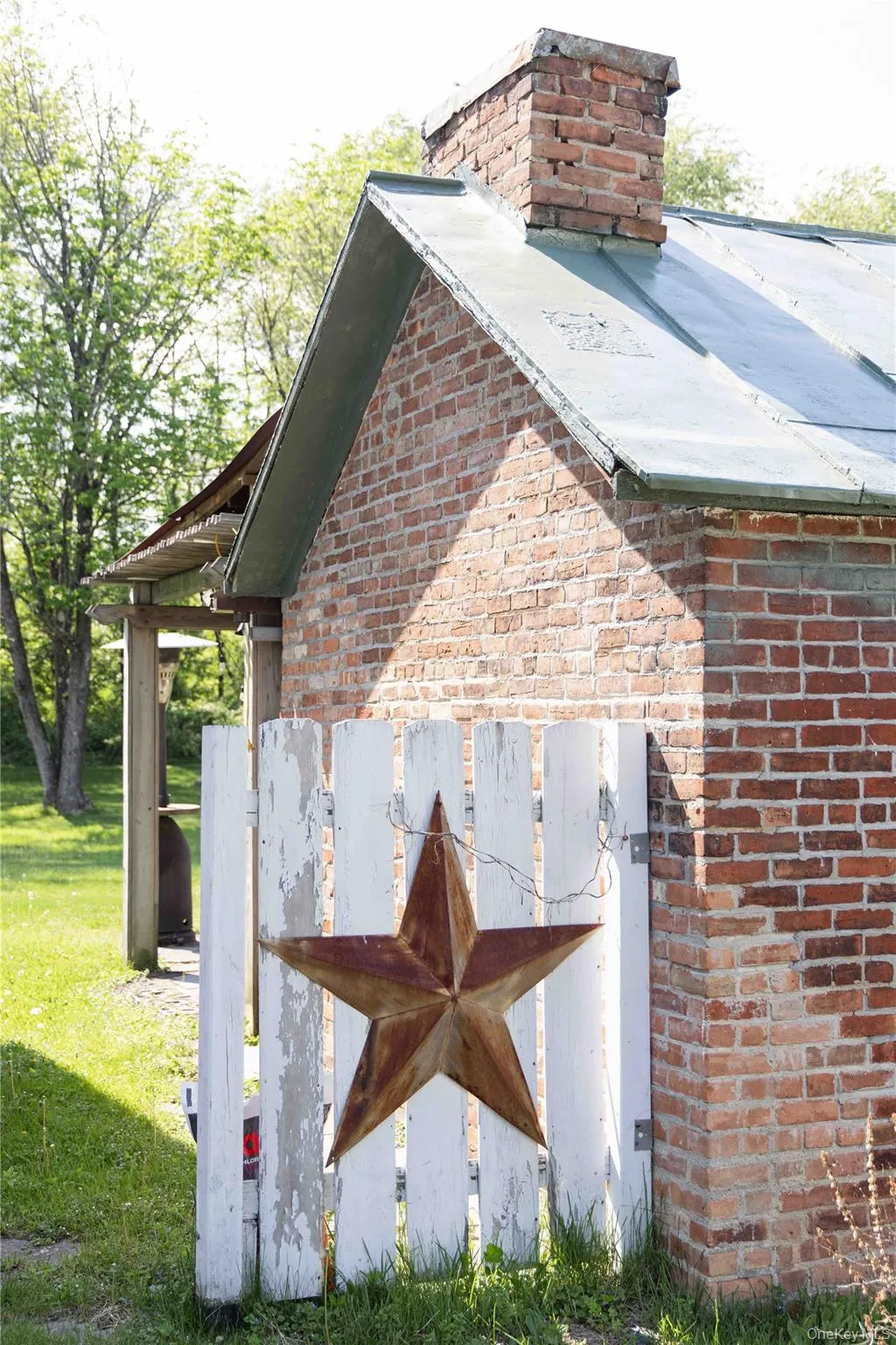 Brick exterior with a metal roof and a prominent brick chimney Brick exterior with a metal roof and a prominent brick chimney