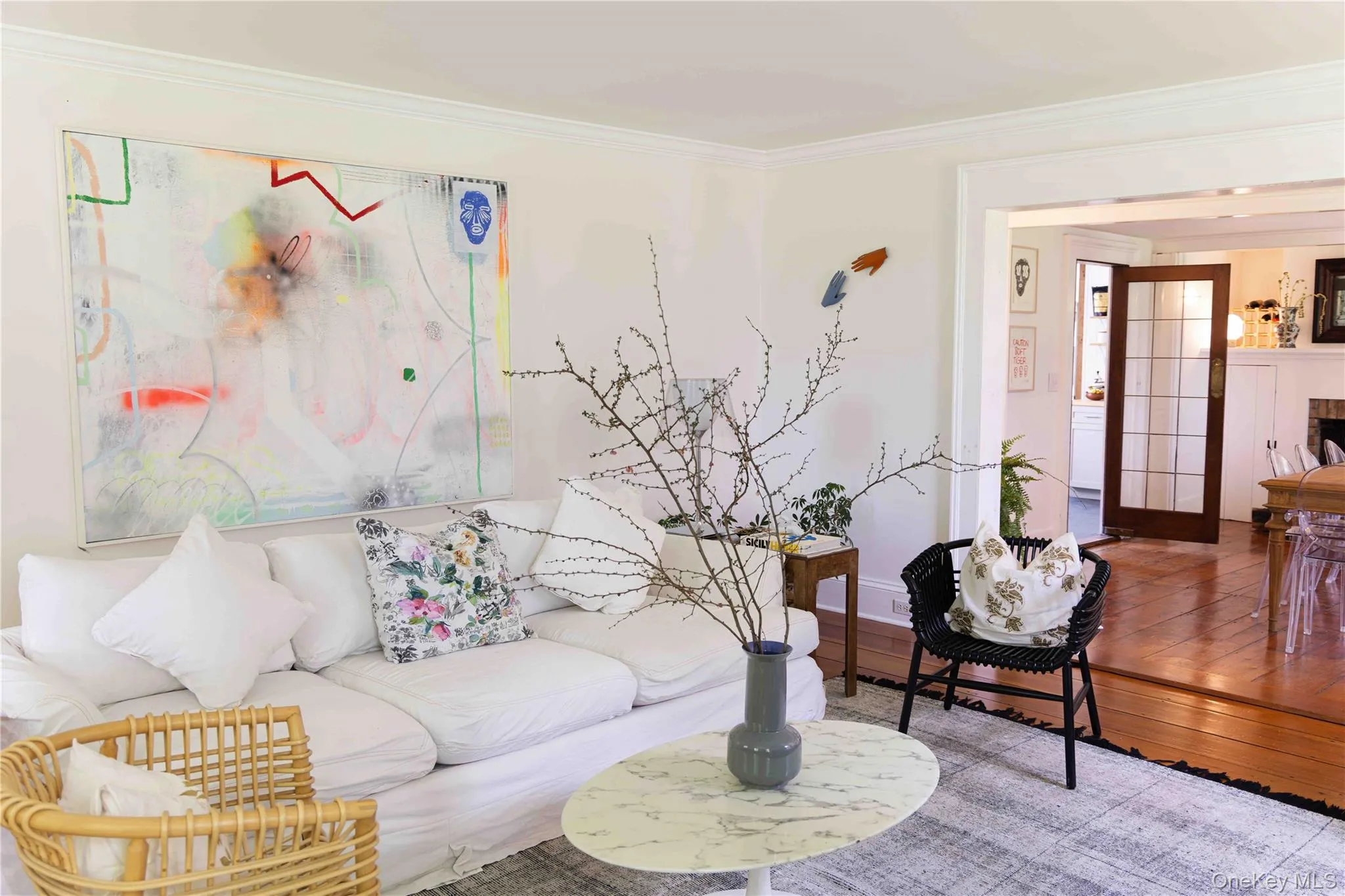 Open-concept living space featuring light-toned walls, crown molding, and wood-finish flooring Open-concept living space featuring light-toned walls, crown molding, and wood-finish flooring