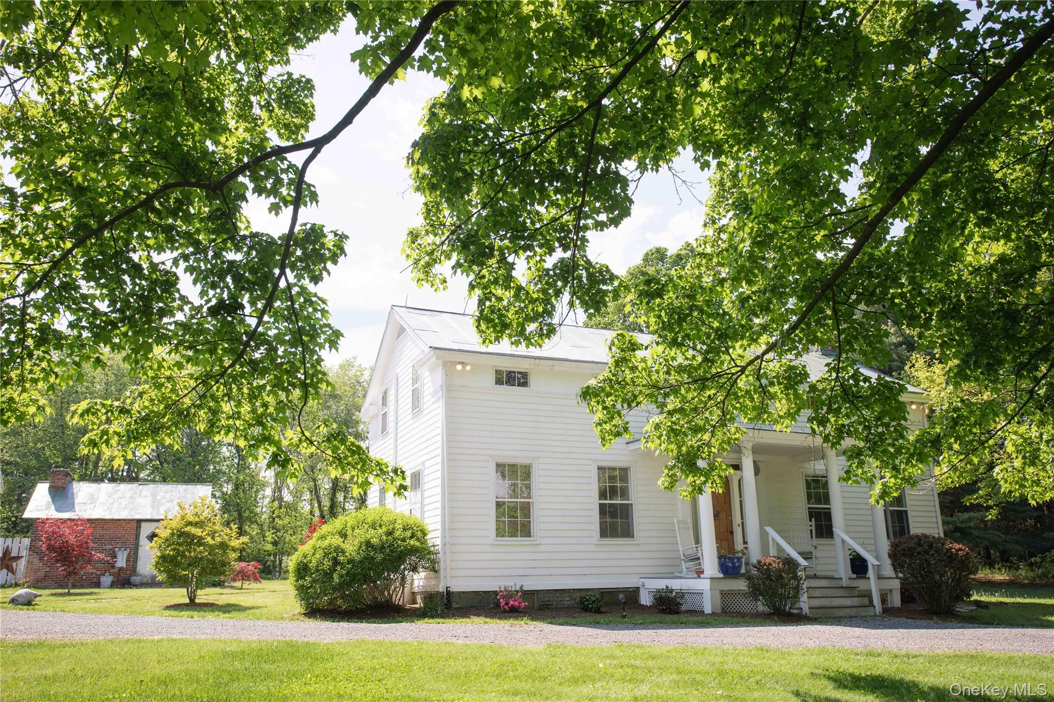 White clapboard siding exterior with a metal roof, featuring a covered front porch with white columns and steps White clapboard siding exterior with a metal roof, featuring a covered front porch with white columns and steps