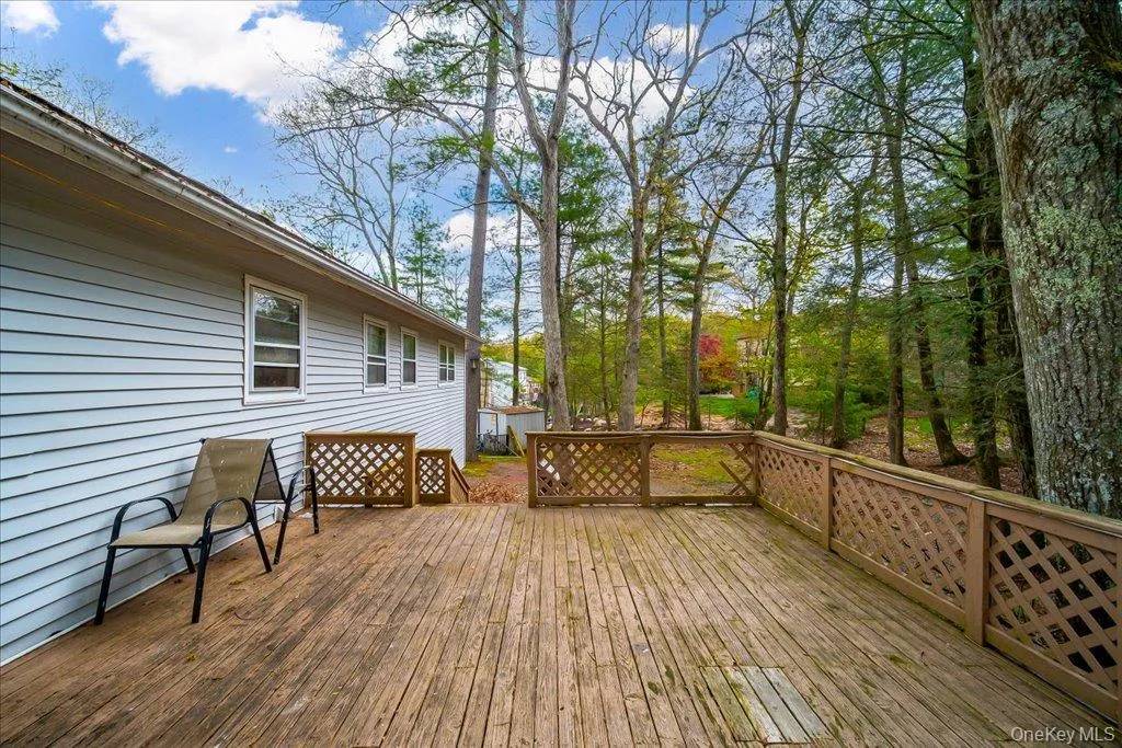 Expansive wood deck with lattice railing, set against a backdrop of mature trees Expansive wood deck with lattice railing, set against a backdrop of mature trees