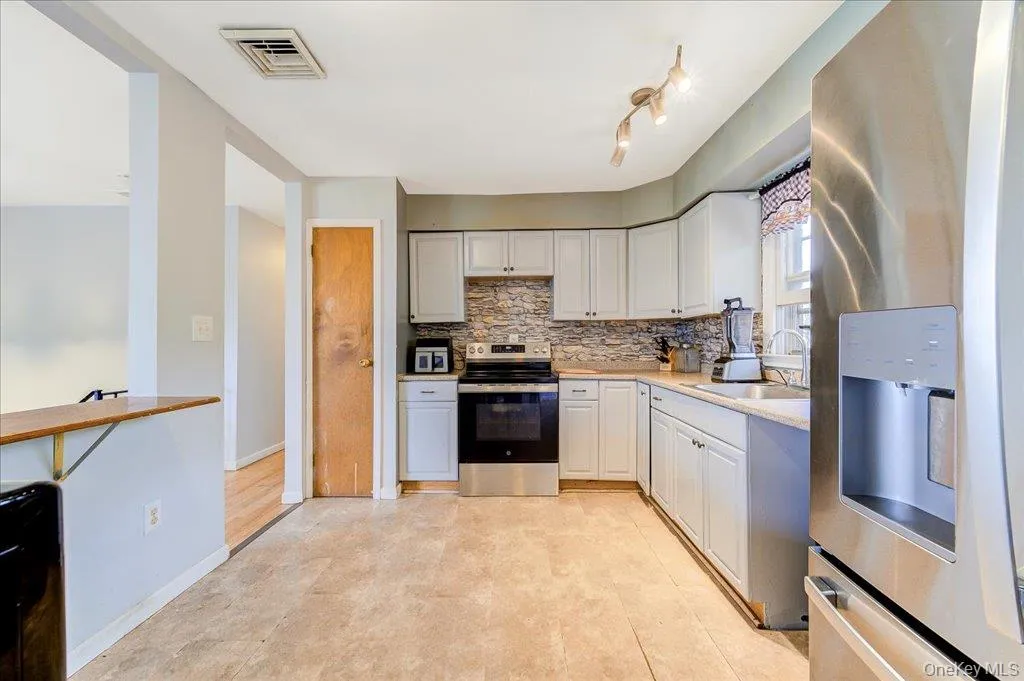 Kitchen with tile flooring, light cabinetry, stone-finish backsplash, stainless steel appliances. Kitchen with tile flooring, light cabinetry, stone-finish backsplash, stainless steel appliances.