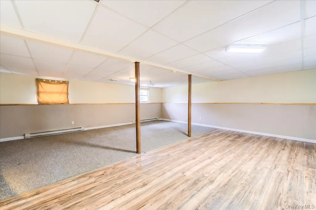 Finished lower level without furniture, featuring wood-finish flooring and carpeting Finished lower level without furniture, featuring wood-finish flooring and carpeting