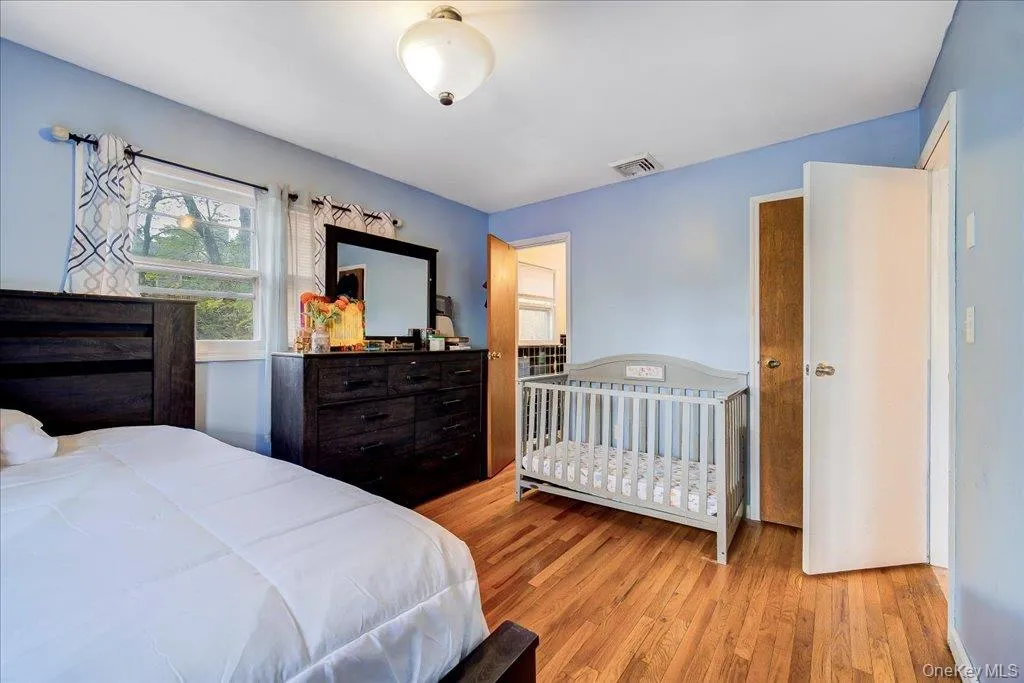 Primary bedroom Hardwood flooring extends throughout this room, featuring a built-in ceiling light fixture and two windows Primary bedroom Hardwood flooring extends throughout this room, featuring a built-in ceiling light fixture and two windows