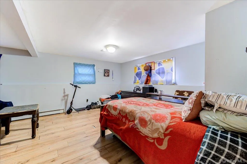 Spacious room featuring wood-finish flooring, white walls with a chair rail, and multiple windows Spacious room featuring wood-finish flooring, white walls with a chair rail, and multiple windows