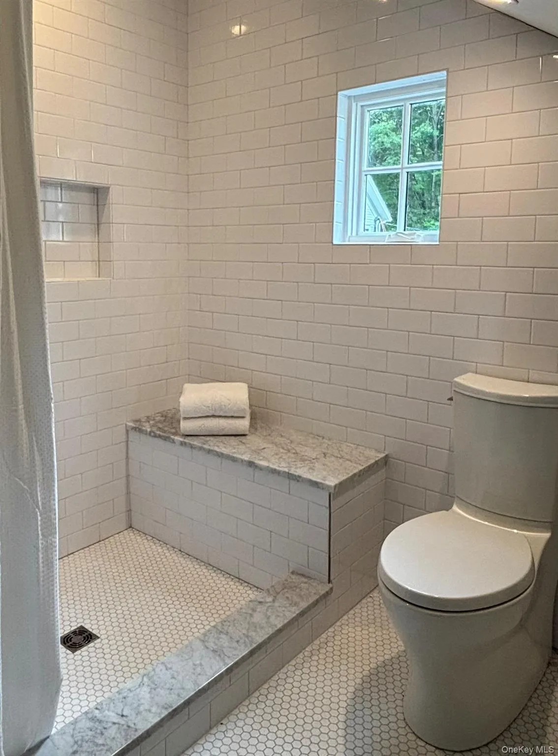 A view of the newly tiled walk-in shower and toilet area. A view of the newly tiled walk-in shower and toilet area.