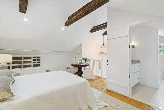A view of the top of the stairs with a desk and chair and a view of into the primary bath with laundry. A view of the top of the stairs with a desk and chair and a view of into the primary bath with laundry.