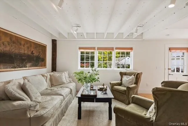 A view of the bright living room and the back door with some of the rustic charm recreated with the original beams. A view of the bright living room and the back door with some of the rustic charm recreated with the original beams.