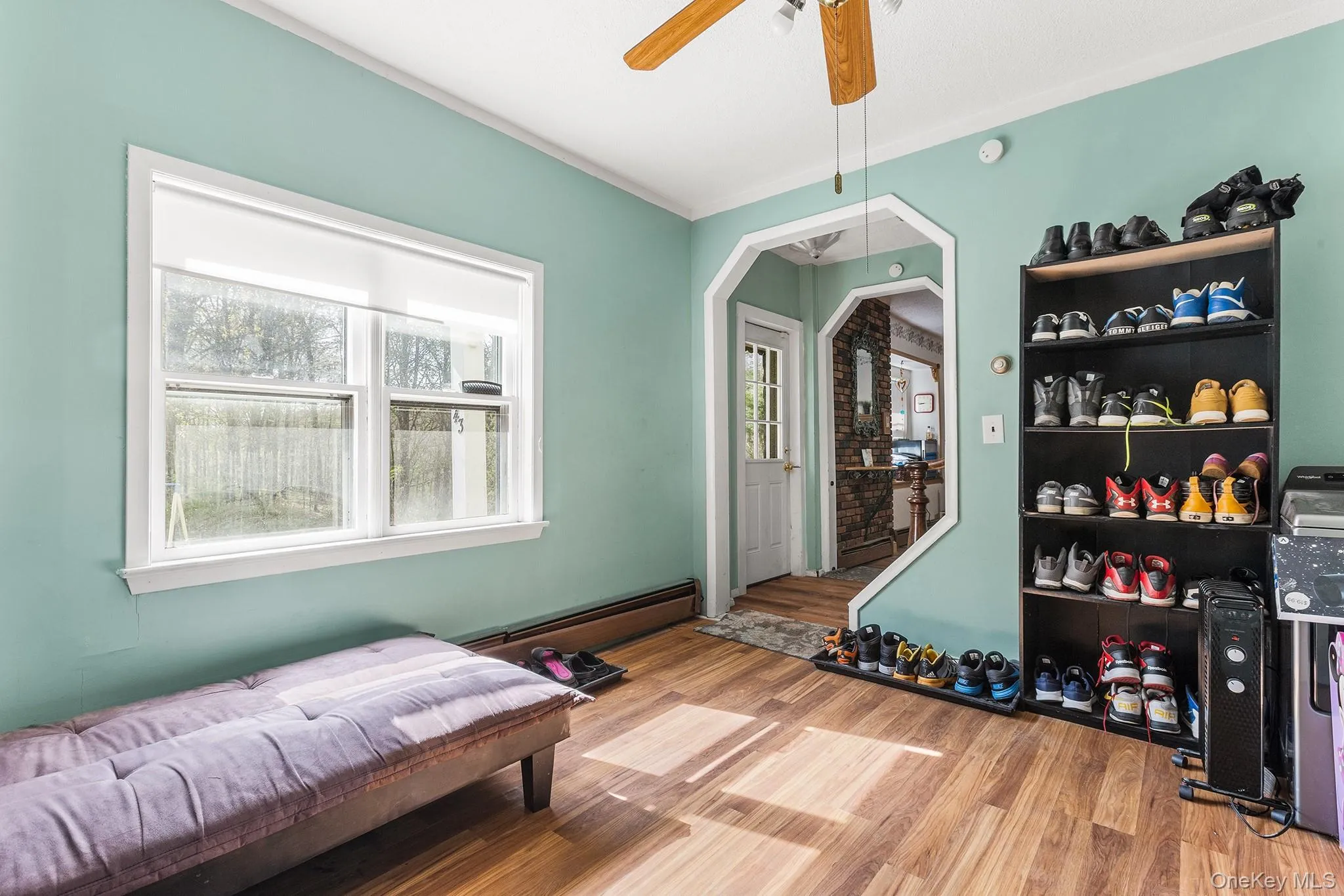 Bright interior space featuring wood-finish flooring, a ceiling fan, and a large window with white trim Bright interior space featuring wood-finish flooring, a ceiling fan, and a large window with white trim