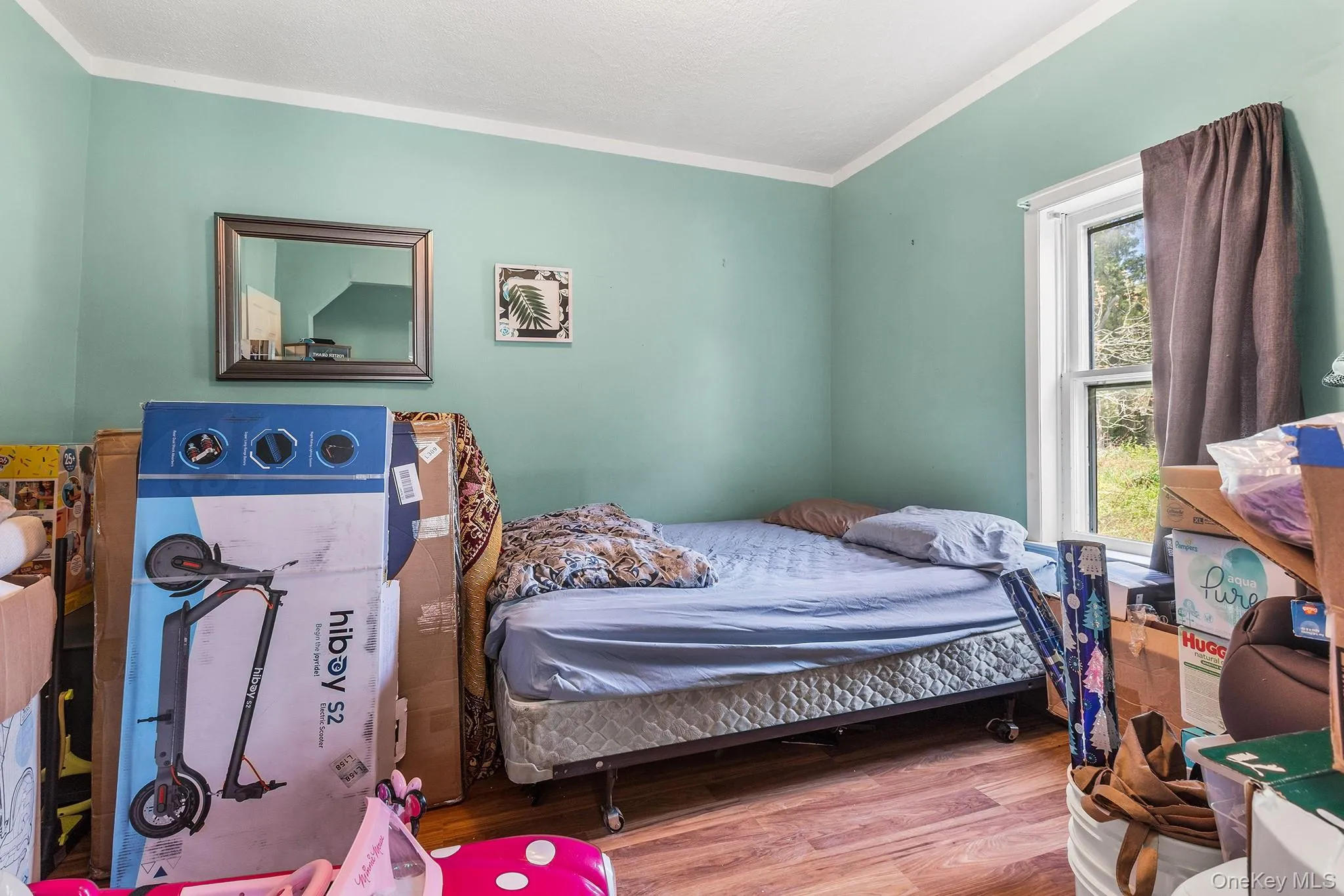 Room featuring wood-finish flooring, a single window, and light-colored wall paint Room featuring wood-finish flooring, a single window, and light-colored wall paint