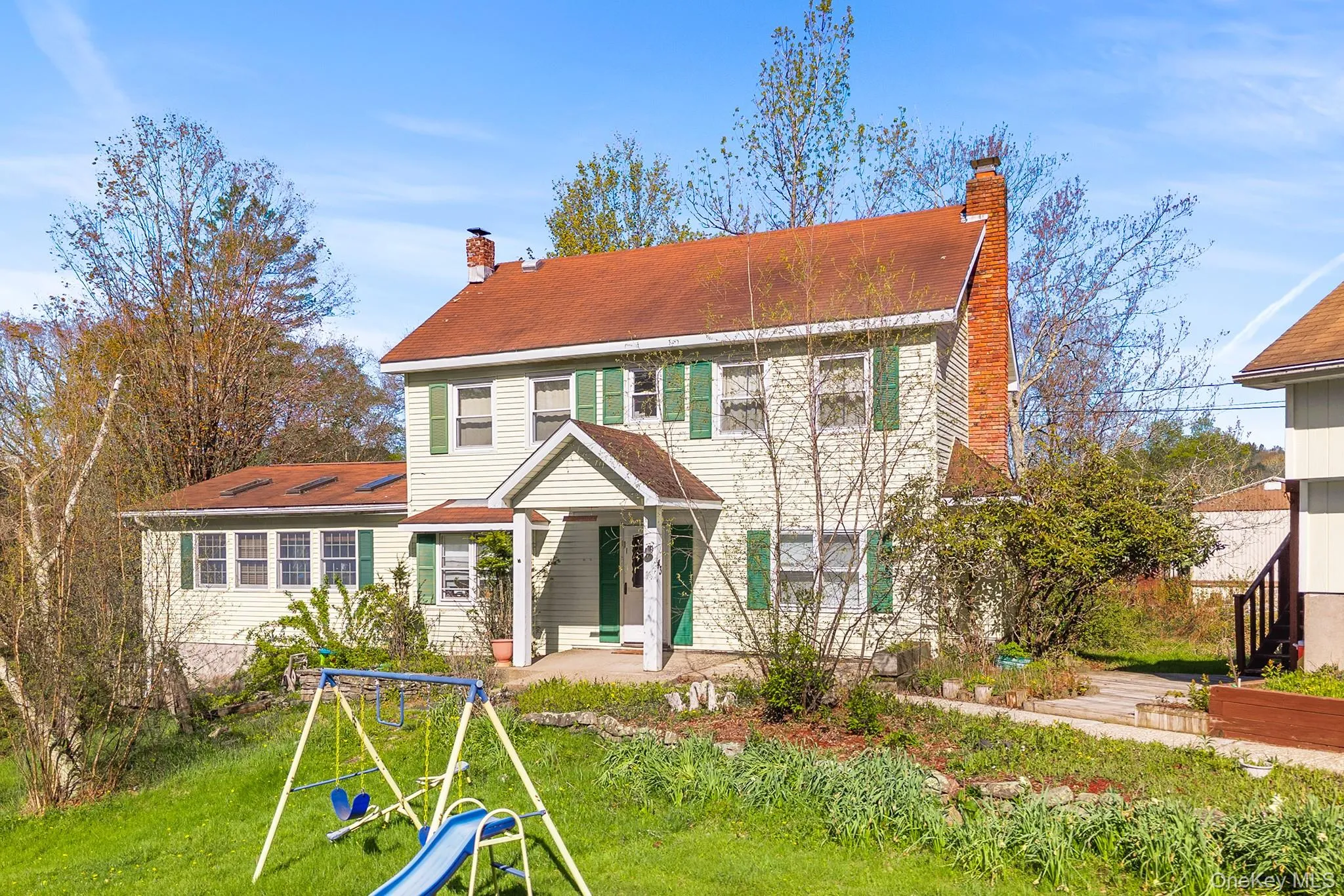 Two-story residence featuring light-colored siding, a red shingle roof, and green window shutters Two-story residence featuring light-colored siding, a red shingle roof, and green window shutters