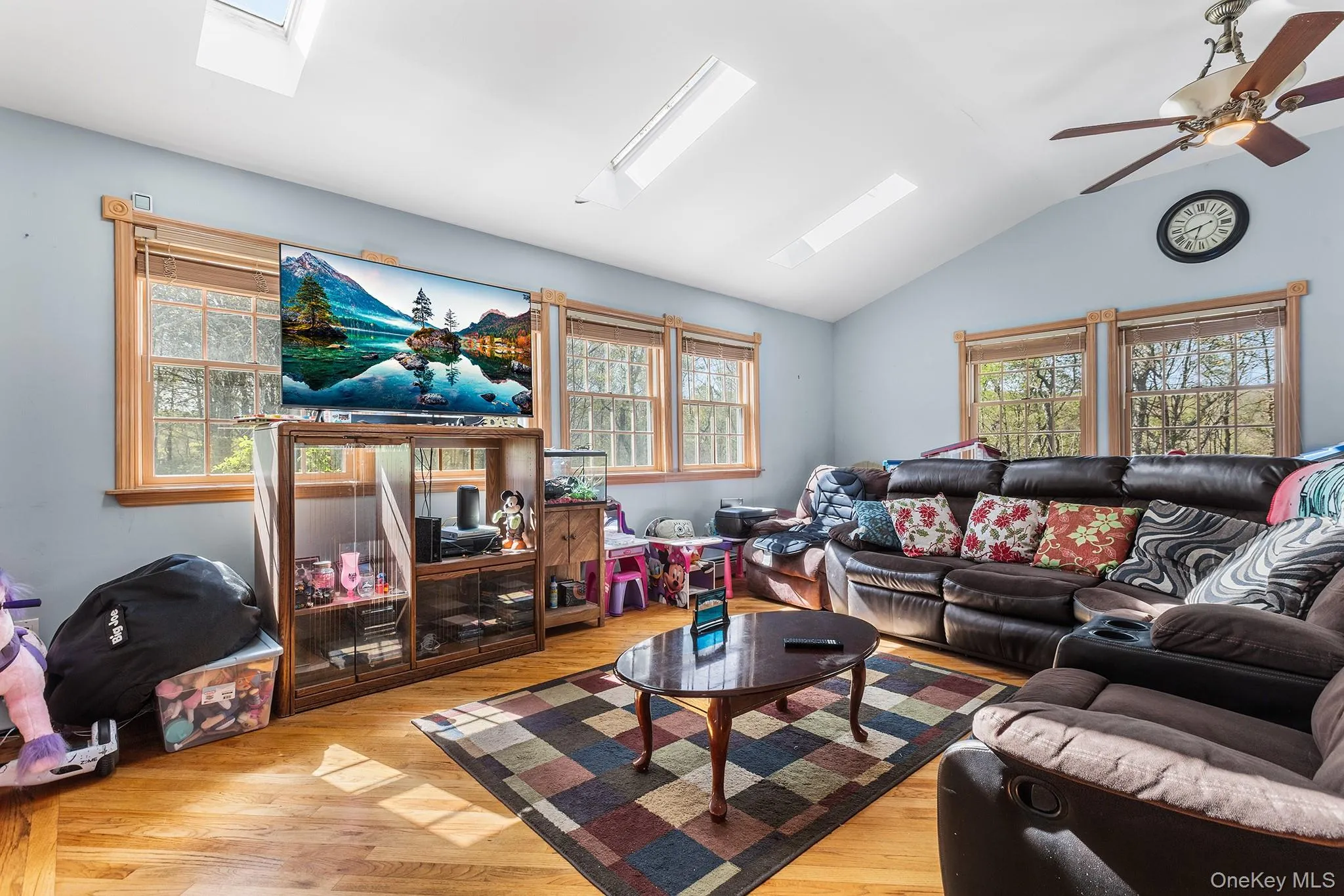 Vaulted ceiling living space featuring hardwood flooring and multiple windows with natural wood trim Vaulted ceiling living space featuring hardwood flooring and multiple windows with natural wood trim
