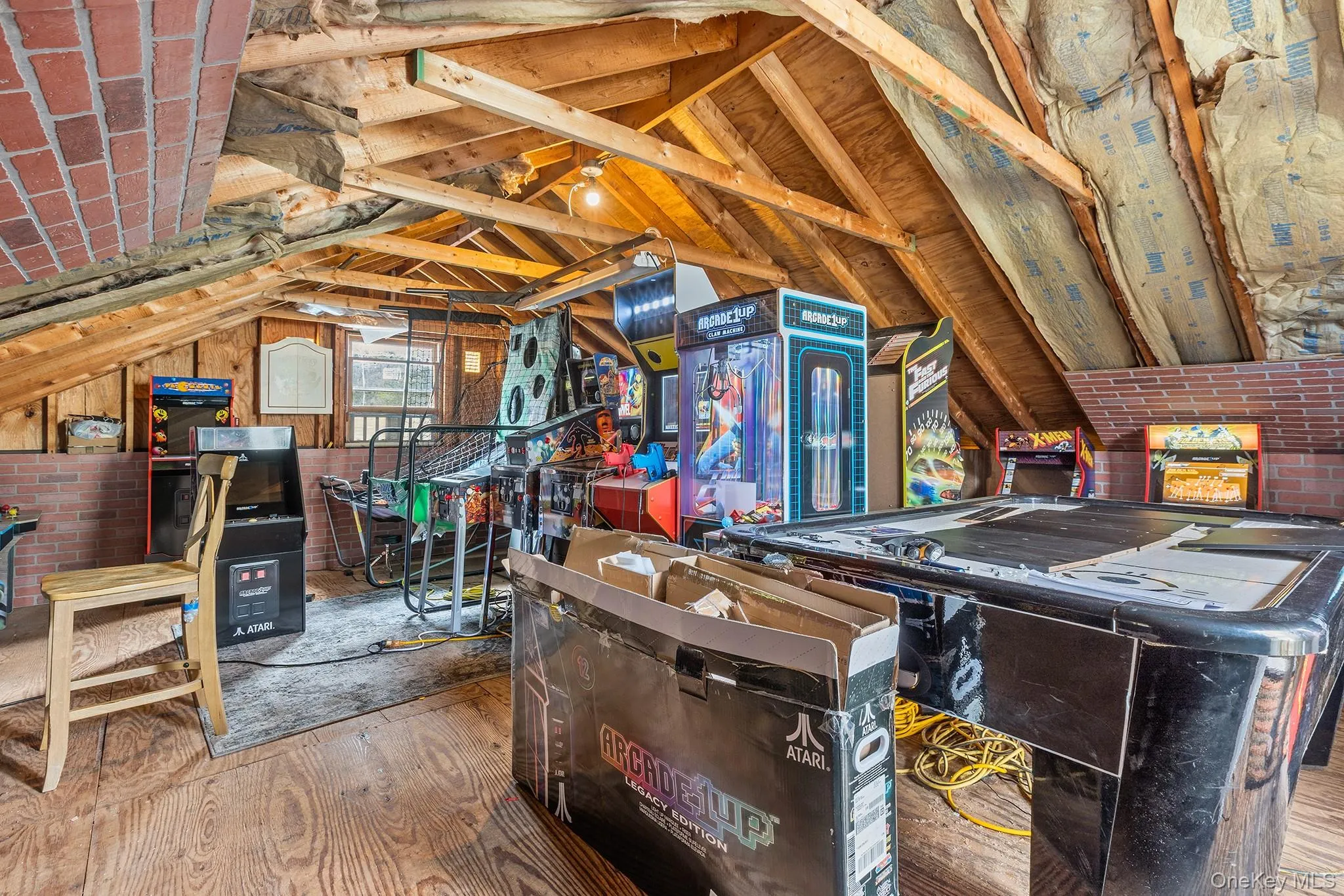Attic space featuring exposed wood beams, wood-finish flooring, and brick accents Attic space featuring exposed wood beams, wood-finish flooring, and brick accents