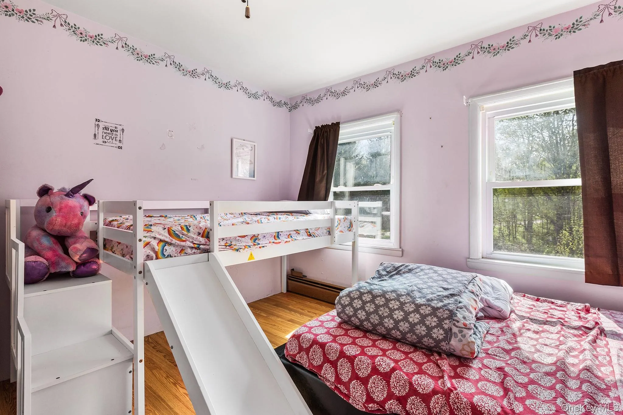 Room featuring natural wood flooring and dual windows with white trim Room featuring natural wood flooring and dual windows with white trim