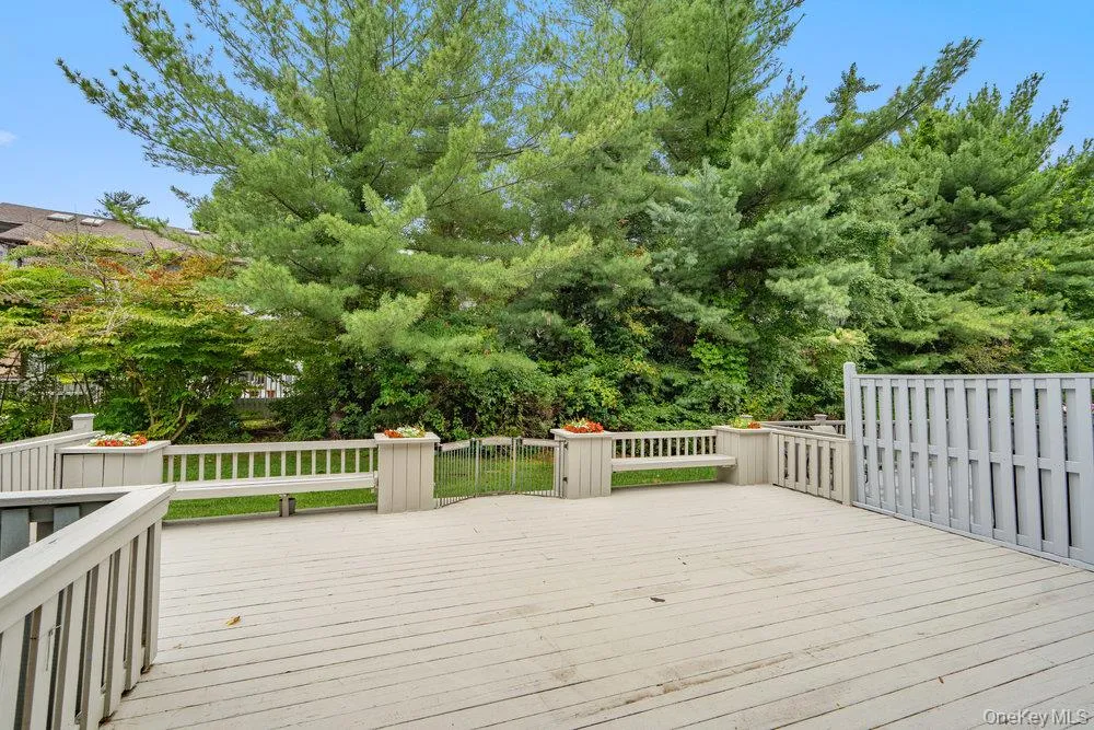 Expansive outdoor deck featuring a light-toned surface, perimeter railings, built-in bench seating, and a privacy fence Expansive outdoor deck featuring a light-toned surface, perimeter railings, built-in bench seating, and a privacy fence
