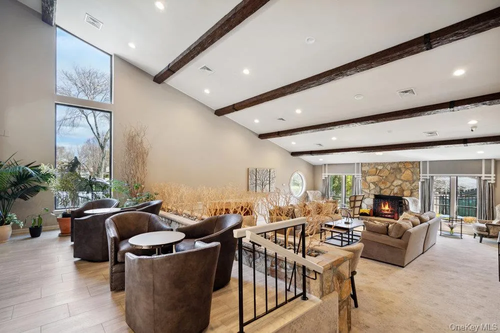 Expansive common area featuring a vaulted ceiling with exposed wood beams, recessed lighting, and large picture windows Expansive common area featuring a vaulted ceiling with exposed wood beams, recessed lighting, and large picture windows