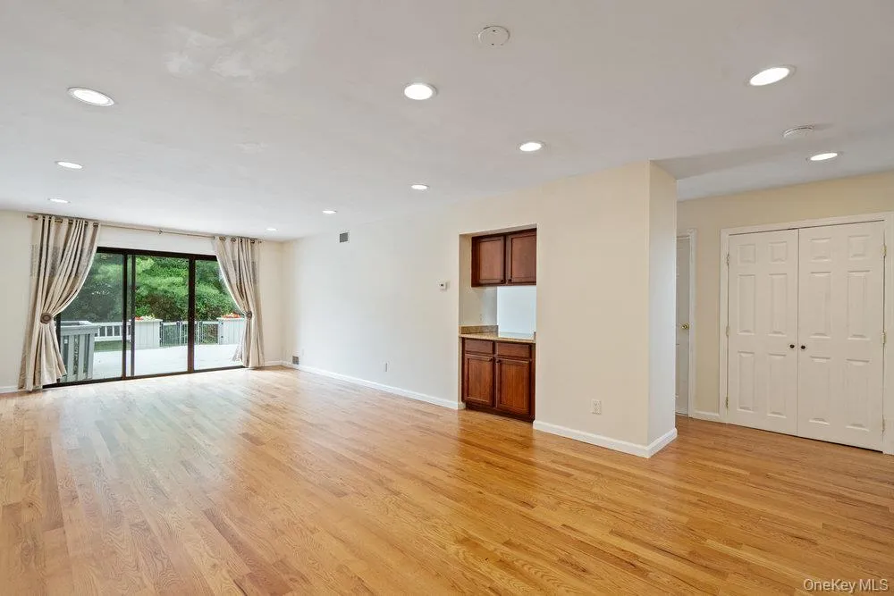 Spacious interior featuring wood-finish flooring, recessed lighting, and a built-in wet bar with wood cabinetry Spacious interior featuring wood-finish flooring, recessed lighting, and a built-in wet bar with wood cabinetry