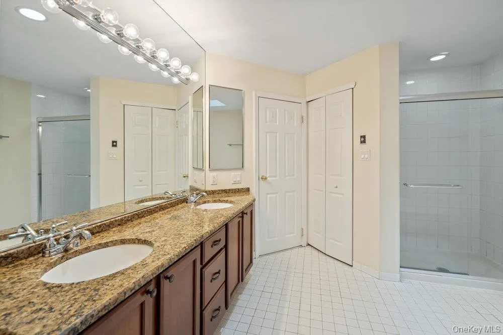 Double vanity with a granite-style countertop, dual undermount sinks, and a full-width mirror Double vanity with a granite-style countertop, dual undermount sinks, and a full-width mirror