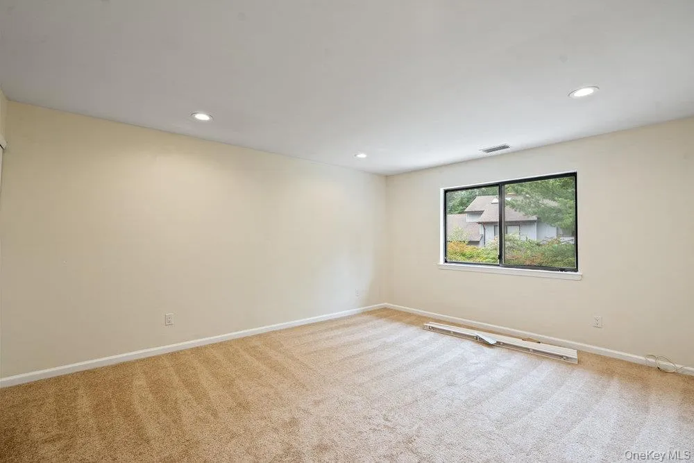 Carpeted room featuring a large window, recessed lighting, and neutral wall tones Carpeted room featuring a large window, recessed lighting, and neutral wall tones