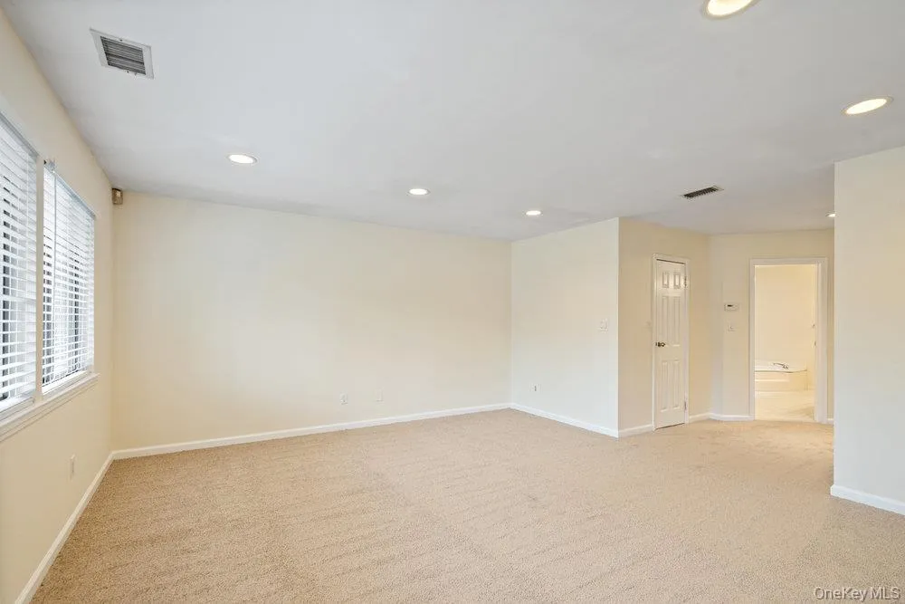 Spacious interior featuring neutral carpet flooring, recessed lighting, and white window blinds Spacious interior featuring neutral carpet flooring, recessed lighting, and white window blinds