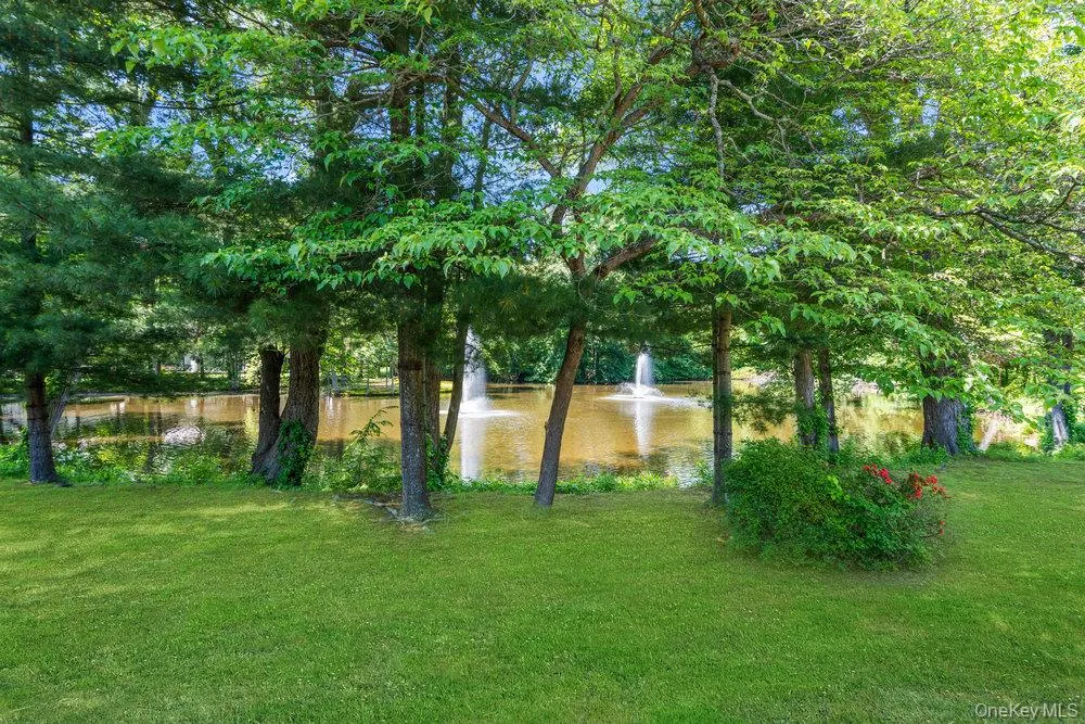 Expansive lawn area featuring mature trees and a tranquil pond with two fountains Expansive lawn area featuring mature trees and a tranquil pond with two fountains