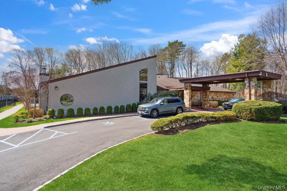 Exterior featuring a stone-clad portico, a pitched roofline, an asphalt drive, and manicured landscaping Exterior featuring a stone-clad portico, a pitched roofline, an asphalt drive, and manicured landscaping