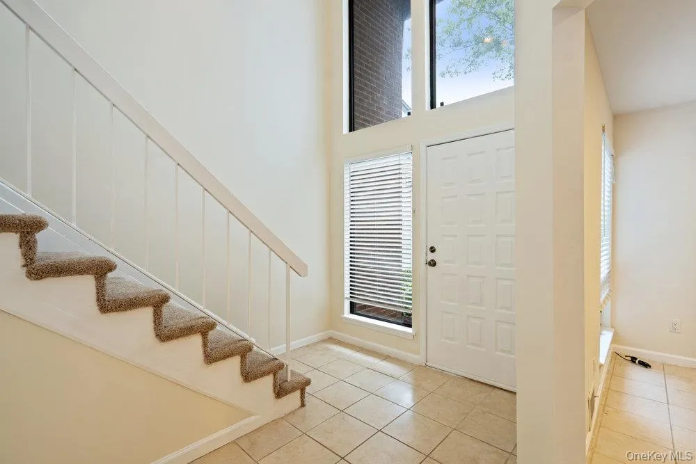 Two-story foyer featuring a paneled door, sidelight windows with blinds, and transom windows Two-story foyer featuring a paneled door, sidelight windows with blinds, and transom windows