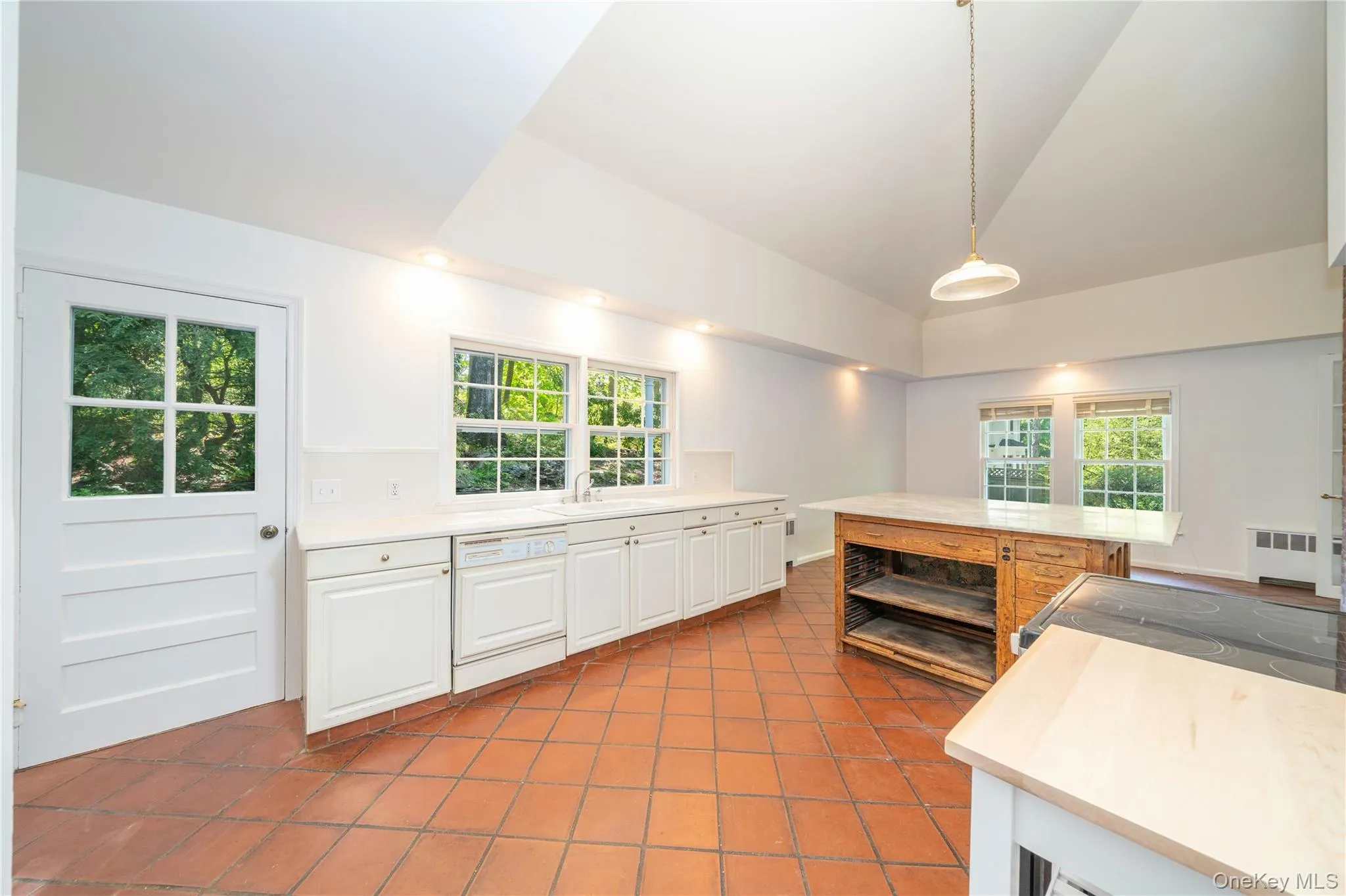 Kitchen features a stone island and door to a pergola. Kitchen features a stone island and door to a pergola.