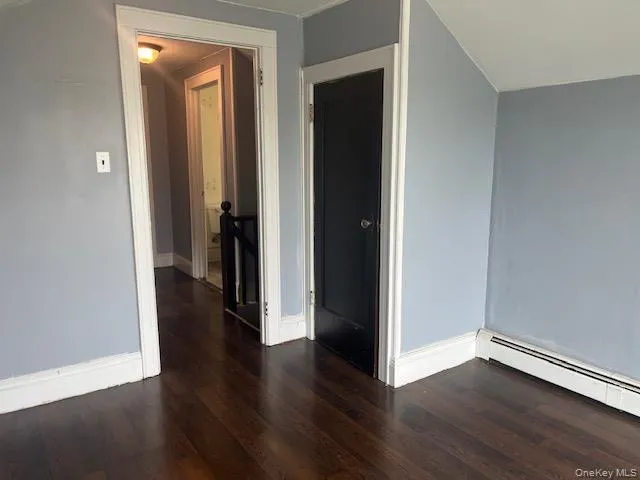 Spare room with baseboard heating and dark hardwood / wood-style flooring Spare room with baseboard heating and dark hardwood / wood-style flooring